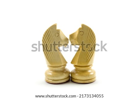 A pair of amorous chess horses stare at each other with love. Happy couple together, romantic relationship. White background concept.