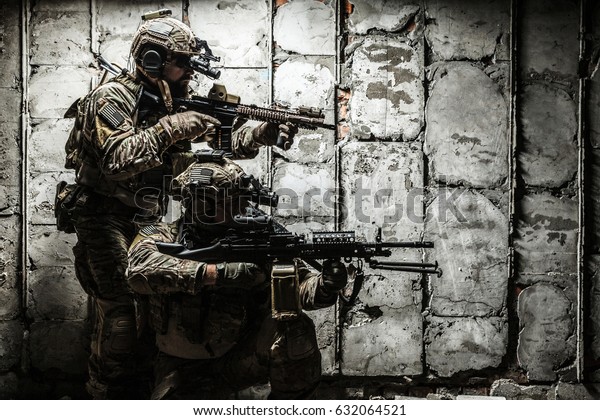 Pair of Army Rangers with\
rifle and machine gun moving along the concrete wall on mission.\
They are ready to start firing if enemy appear. Outdoor location\
shot