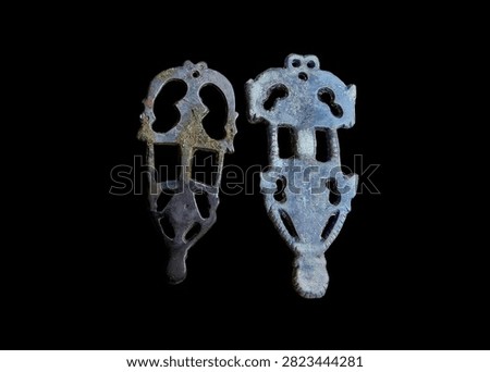 Pair of authentic ancient Early Slavic bronze brooches. Anthropomorphic and zoomorphic openwork fibulae of Penkovka culture, Early Middle Ages artifacts isolated on black background.