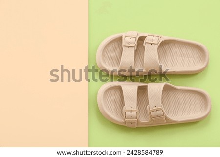 Pair of beige flip flops on colorful background