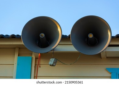 Pair Of Big Retro Loudspeakers The Roof Outside Against Blue Sky. Urgent Or Emergency Announcement Concept. Closeup The Speaker Mounted. The Public Voice Warning System Is Installed On The Building.