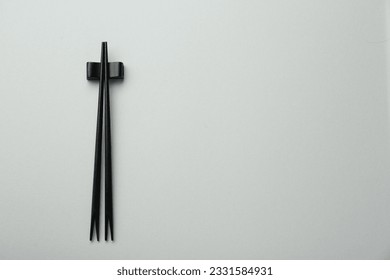 Pair of black chopsticks with rest on light grey background, top view. Space for text - Powered by Shutterstock