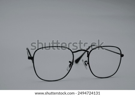 A pair of black, rectangular glasses with clear lenses rests on a gray surface. The glasses are slightly askew, suggesting a sense of disorientation or neglect.