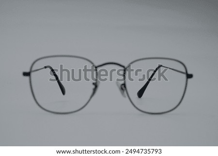 A pair of black, rectangular glasses with clear lenses rests on a gray surface. The glasses are slightly askew, suggesting a sense of disorientation or neglect.