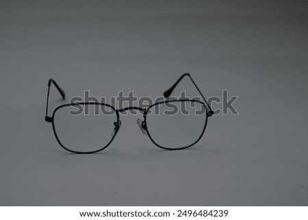 A pair of black, rectangular glasses with clear lenses rests on a gray surface. The glasses are slightly askew, suggesting a sense of disorientation or neglect.
