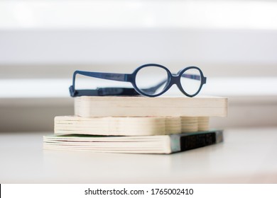 Pair Of Blue Child Kid Glasses On Top Of Stack Of Children's Books