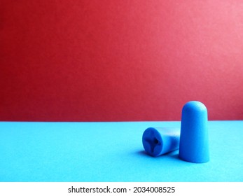Pair of blue earplugs on a burgundy-blue blur background - Shutterstock ID 2034008525