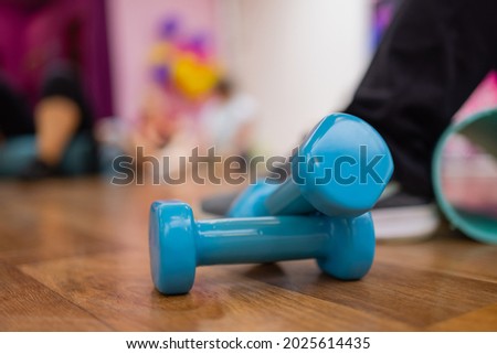 A pair of blue hard plastic hex dumbbells lying on the rubber matted floor of a gym or health club.