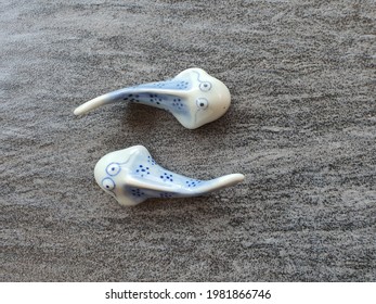 A pair of blue porcelain  pottery catfish or tadpole on the textured floor as background. Collectible miniature and hobby. Vice versa. Opposite. Ying yang