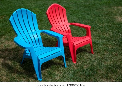 Pair Of Blue And Red Plastic Lawn Chairs On A Grass Lawn