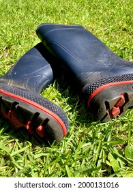 Pair Of Blue Rubber Work Boots Tossed Aside On Green Grass After Doing Chores