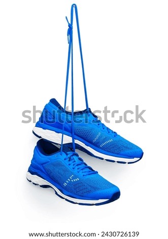 A pair of blue running shoes hanging from a hook. Isolated on a white background.