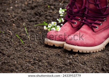 Pair of boots and flowers on soil in the ground in nature