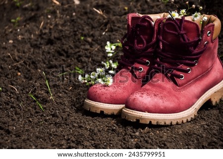 Pair of boots and flowers on soil in the ground in nature