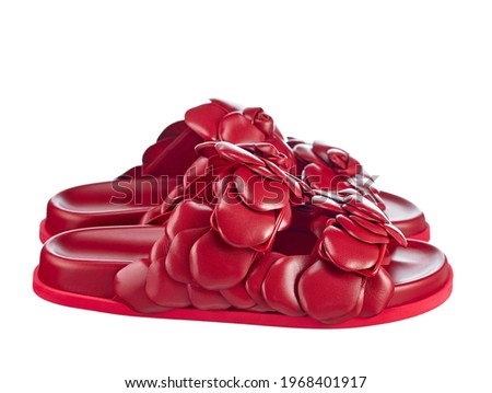 Pair of bright red women's leather sandals decorated with genuine leather flowers and isolated on a white background. Side view.Comfortable elegant walking shoes for the summer season.