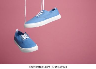 Pair of bright stylish shoes hanging against color background. Space for text - Powered by Shutterstock