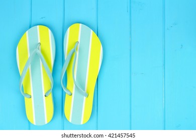 Pair of bright summer flip-flops against a blue wooden background - Powered by Shutterstock