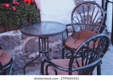 A pair of chairs and a table set up on a city sidewalk.