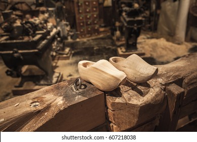 Pair of clogs made of poplar wood. Klompen, traditional Dutch shoes for everyday use stand on wooden beam in manufacturing facility