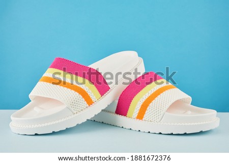 Pair of colorful multicolored rainbow flip flops or sandals on pastel background. Beach holidays and Summer concept.
