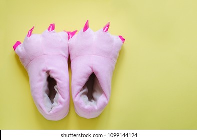 Pair Of Cute Pink Monster Foot Slippers With Big Claws On Yellow Background. Pop Art Style. Copy Space. Top View.