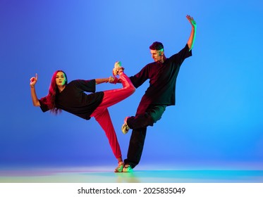 Pair Dance. Two Young People,man And Woman Dancing Contemporary Dance Over Blue Background In Neon Light. Youth Culture, Modern Dance Aesthetics Concept