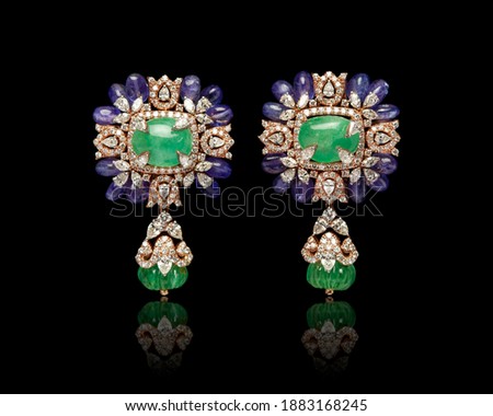 Pair of designer Earrings with gem stones and diamonds isolated over black background