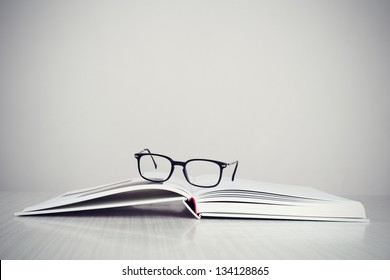 A pair of designer glasses on an opened coffee table book.