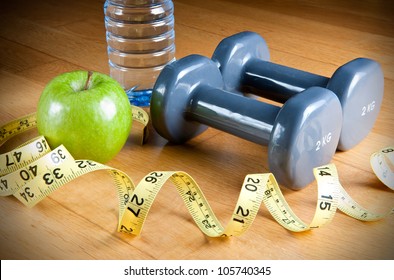 Pair Of Dumbbells, Green Apple, Measuring Tape And Bottle Of Water. Exercise And Healthy Diet Concept.