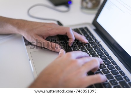 pair of dynamic hands typing and scrolling on a laptop computer working, designing, comunicating and researching, computer with an external hard drive USB connected on a table. 