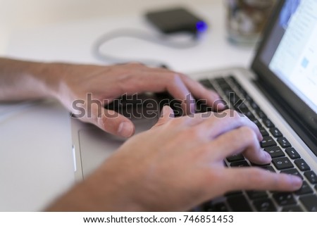 pair of dynamic hands typing and scrolling on a laptop computer working, designing, comunicating and researching, computer with an external hard drive USB connected on a table. 