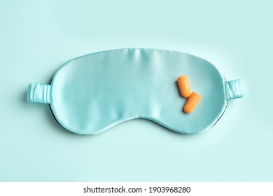 Pair Of Ear Plugs And Sleeping Mask On Turquoise Background, Flat Lay