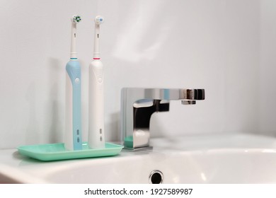 Pair of electric toothbrushes on a turquoise stand next to the faucet. Personal hygiene or dentistry concept