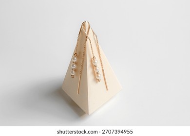 A pair of elegant threader earrings crafted from rose gold. Each earring  features a delicate, long chain that threads through the ear with three small pearls. 