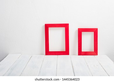 pair of empty red picture frames on white wooden table
