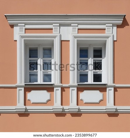 Pair facade windows decorated with portico and pilasters