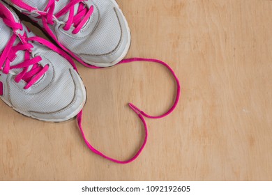 A pair of fashion trendy trainers with heart on wooden background.Copy space.