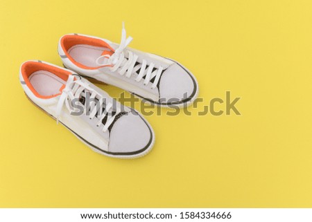 A pair fashion white sneakers on yellow background