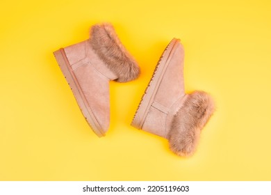 un par de botas de ugg de invierno de moda sobre fondo amarillo, nuevo par