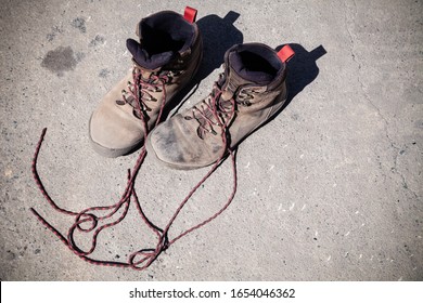 Pair Of Favorite, Worn And Dirty High-altitude Trekking Boots Covered In Mud And Shoelaces, Top View. Concept Travel, Hiking, Walking In Mountains.