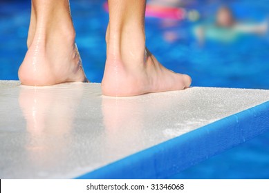 Pair of feet at edge of diving board, waiting for pool to clear before jumping