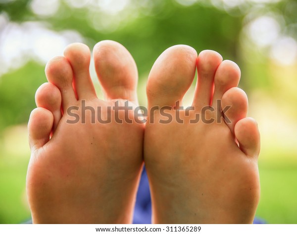 a pair of feet on all ten toes\
(VERY SHALLOW DOF - big toe on the right) in a park\
setting