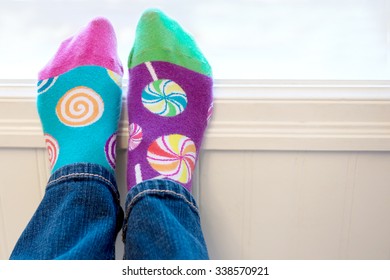 A Pair Of Feet Wearing Brightly Colored Odd Socks