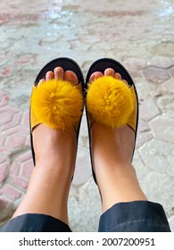 A Pair Of Feet Wearing Furry Yellow Sandals