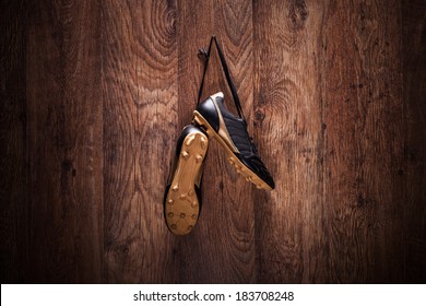 Pair Of Football Boots Hanging On A Wooden Wall.