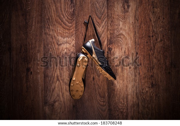Pair of\
football boots hanging on a wooden\
wall.
