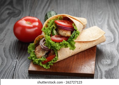pair of fresh juicy tortilla wraps with chicken and vegetables, on table