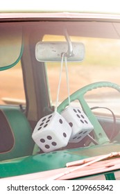 Pair Of Fuzzy Dice Hanging From The Rearview Mirror Of An Antique Car