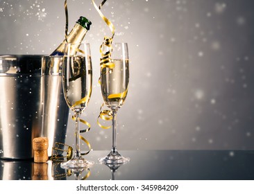 Pair glass of champagne with bottle in metal container. New Year celebration theme with blur spots of bubbles