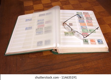 Pair of glasses sitting on a philatelic stamp collection album